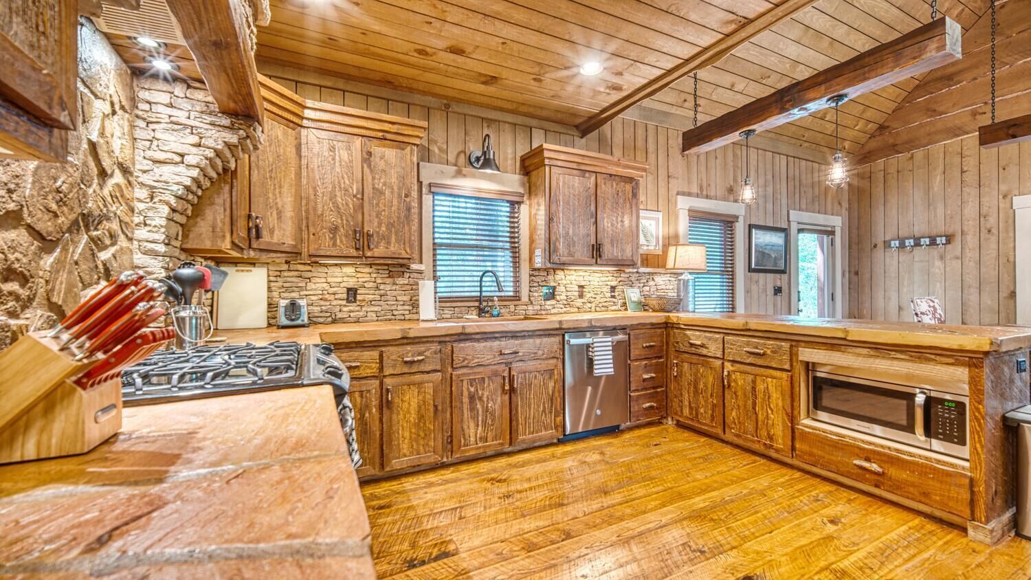 Une cuisine rustique avec des armoires en bois, un mur en pierre et un plancher en bois.