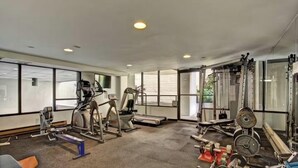 Uma academia com máquinas de cardio, equipamentos de musculação e amplas janelas.