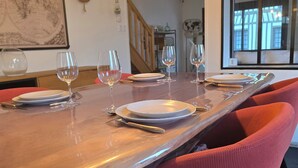 A dining area with a long table, multiple chairs, and wine glasses set for a meal.