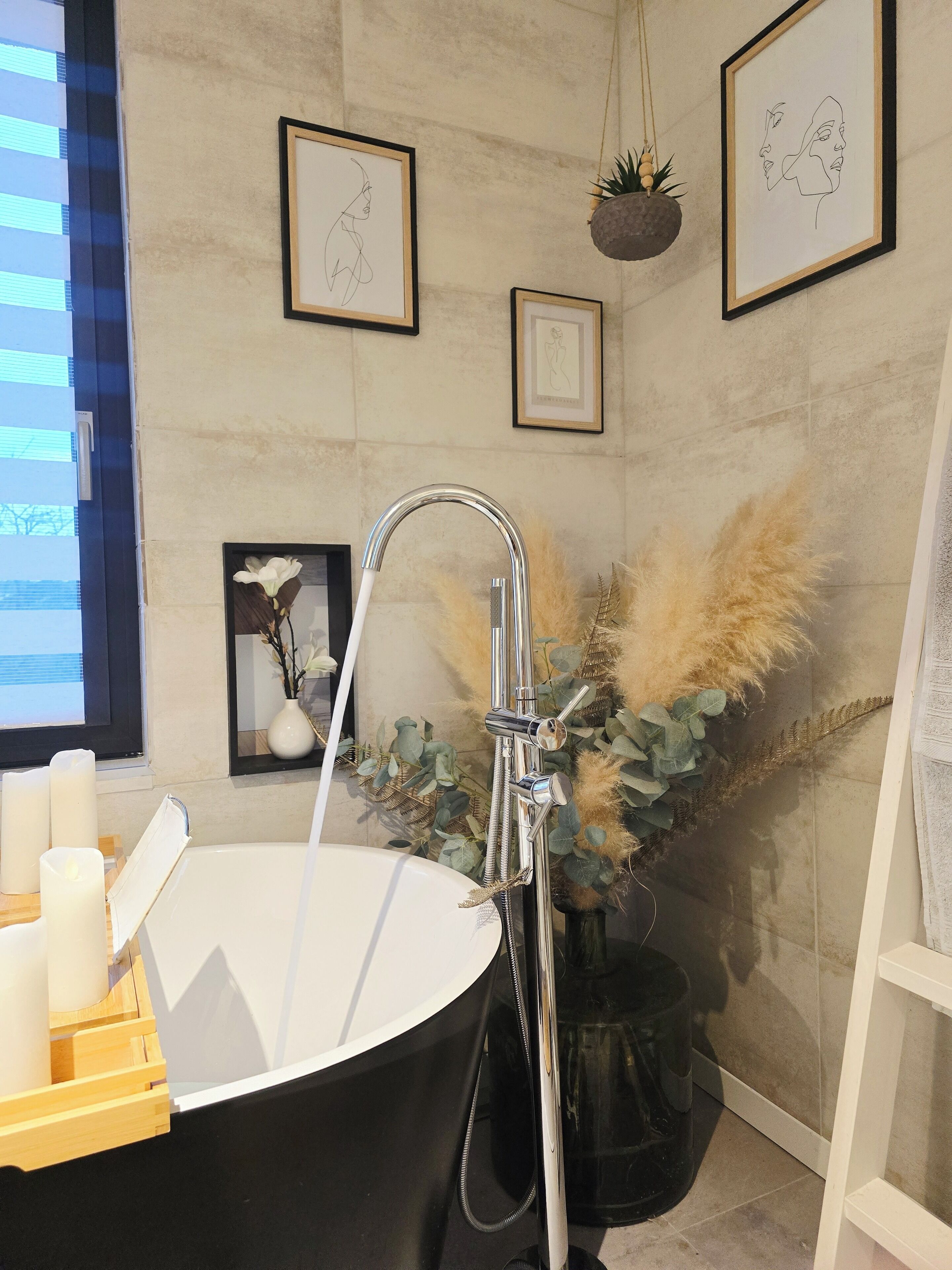 Une salle de bain moderne avec une baignoire sur pieds, une douche murale et des œuvres d’art encadrées.