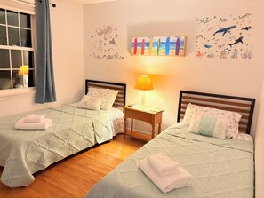 Ein Zweibettzimmer mit zwei Betten, einem Nachttisch, einer Lampe und einem Wandbild.
