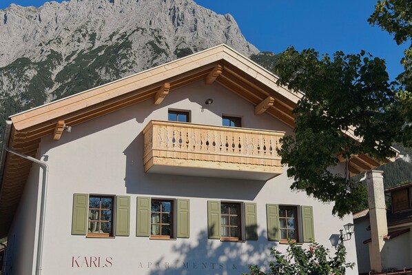 A building with a balcony, multiple windows, and a mountain backdrop. - Karls Design Apartments Mittenwald (Mittenwald)