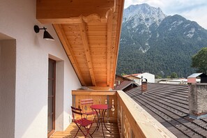 A wooden balcony with a table and chairs, overlooking a mountainous landscape. - Karls Design Apartments Mittenwald (Mittenwald)