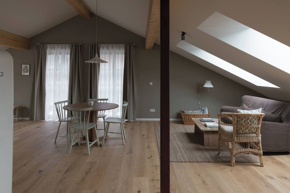 A spacious loft with a dining area, a sofa, and a wicker chair.