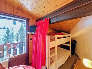 A cozy cabin room with a bunk bed, a window overlooking a snowy landscape, and a small desk with a chair. - Bright studio with mezzanine and south-facing balcony, near slopes (La Chapelle-d'Abondance)