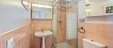 A bathroom with a glass-enclosed shower, a pedestal sink, and a toilet.