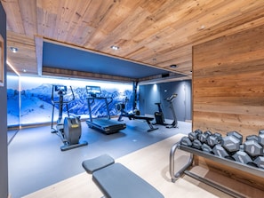 Une salle de sport équipée de matériel d’exercice, d’un banc et d’haltères.