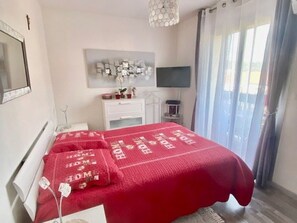 Ein Schlafzimmer mit einem Bett, einem Nachttisch, einer Lampe und einem Fernseher an der Wand.