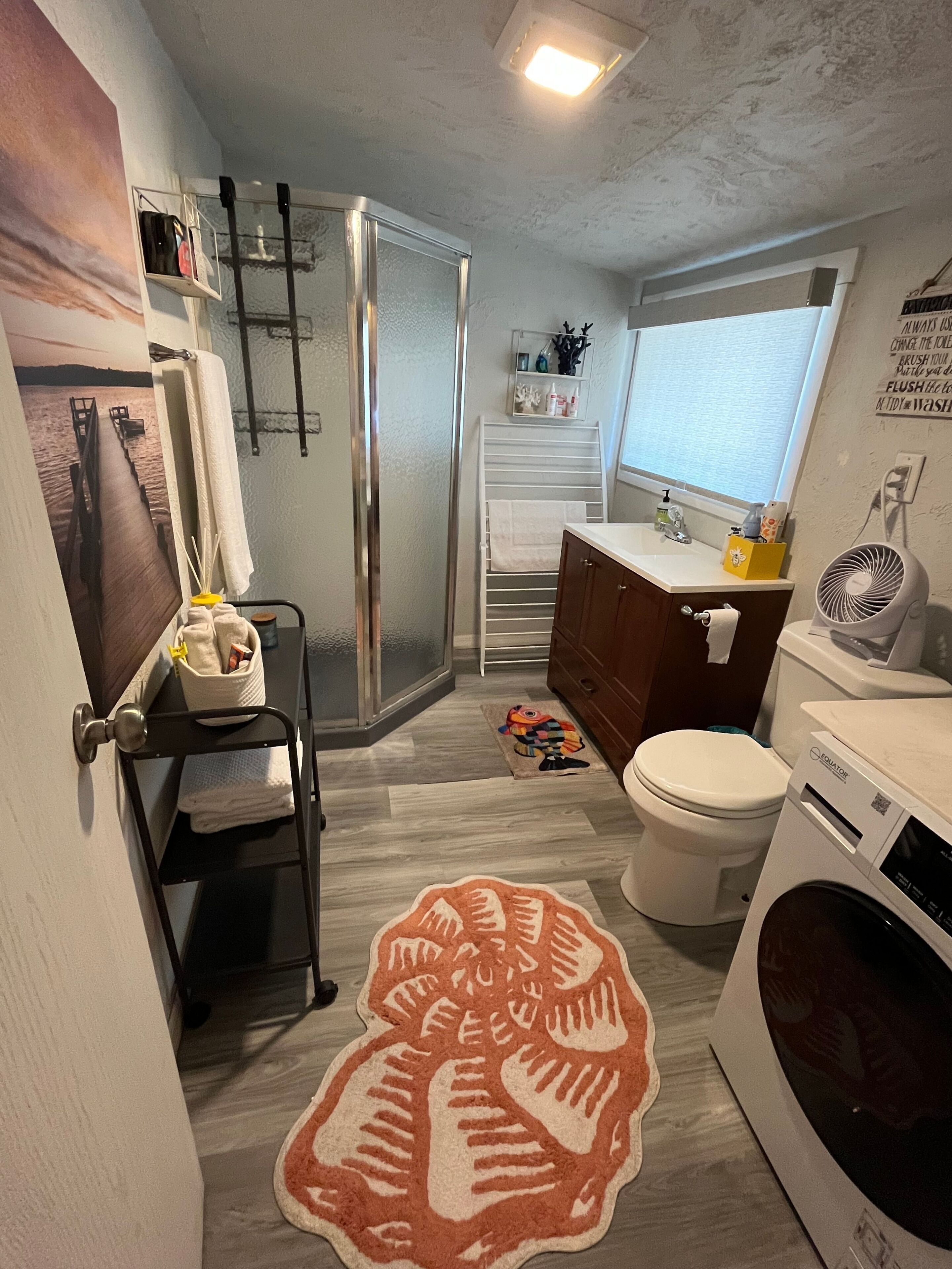 A compact bathroom with a shower, toilet, and washing machine.