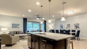 A modern kitchen with a central island, dining area with chairs, and a living room with a sofa. - Free Pool Heat+BBQ|Fam Resort|Themed Frozen + Harry Potter|Star Wars Gameroom (Kissimmee)