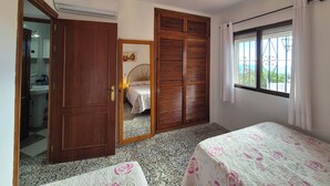 Ein Schlafzimmer mit Bett, Schrank, angrenzendem Badezimmer und Fenster mit Aussicht.
