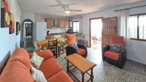 Ein Wohnzimmer mit einer Couch, Stühlen, einem Tisch und einer Küche im Hintergrund.