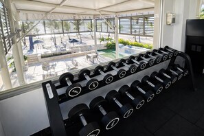 A gym with a rack of dumbbells, a water cooler, and a view of an outdoor patio area. - Beachfront 2bedRm 2Bath Apt G1-3 PlayaNuevaRomana w/Pool,JacuziSpa,GolfTenis,Gym (Playa Nueva Romana)