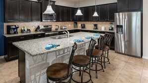 Eine moderne Küche mit dunklen Schränken, Edelstahlgeräten, einer Granit Arbeitsplatte und einer Bar mit Hockern.