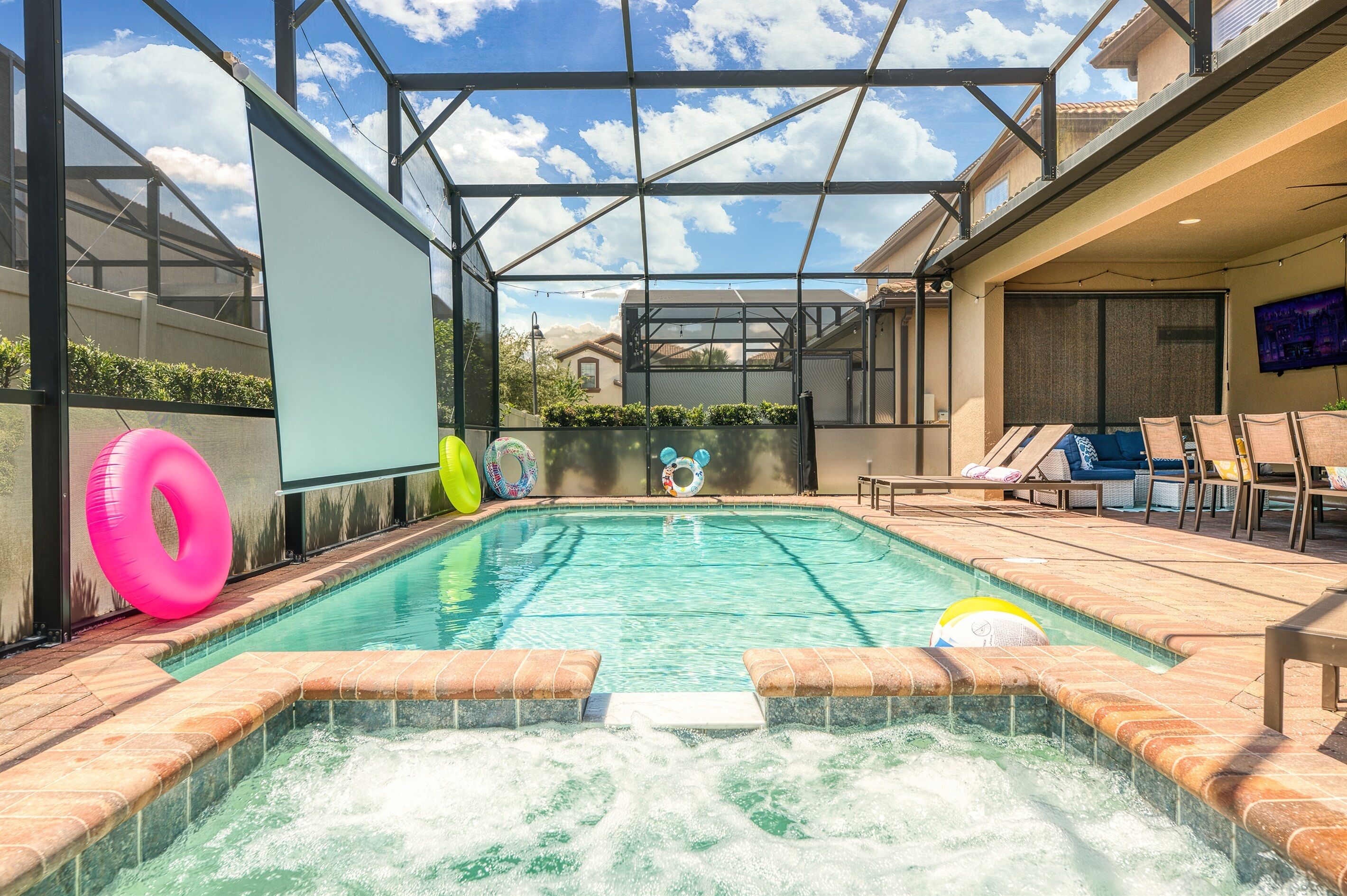 Une piscine avec un jacuzzi, des chaises longues et des bouées gonflables.