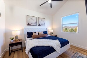 Una camera da letto con un letto, due comodini, una ventola a soffitto e un'ampia finestra con vista.