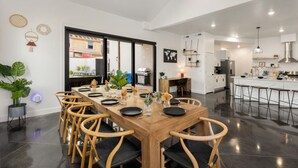 A modern kitchen with a large island, built-in appliances, and a dining area with a wooden table and chairs. - Shadow Stone | Private Pool & Spa | 16+ Guests! (Hurricane)