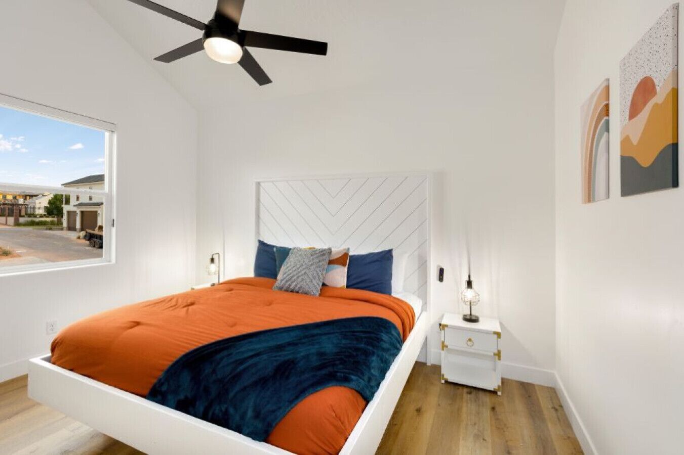 Une chambre à coucher moderne avec un lit, un ventilateur de plafond, une table de chevet et une fenêtre.