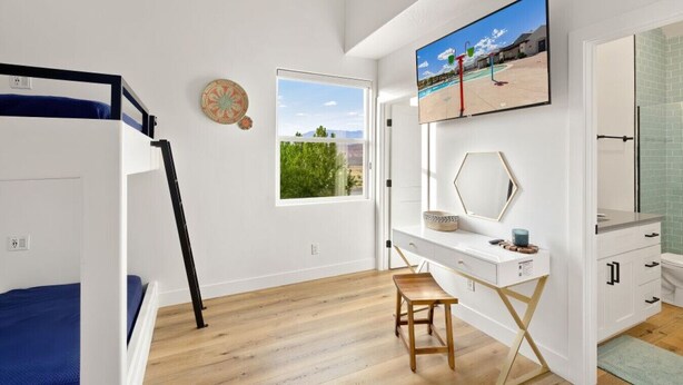 Una camera da letto con un letto a castello, una scrivania con uno specchio, una TV e una finestra vista verde.