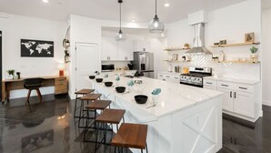 A modern kitchen with a large island, white cabinetry, and stainless steel appliances. - Shadow Stone | Private Pool & Spa | 16+ Guests! (Hurricane)