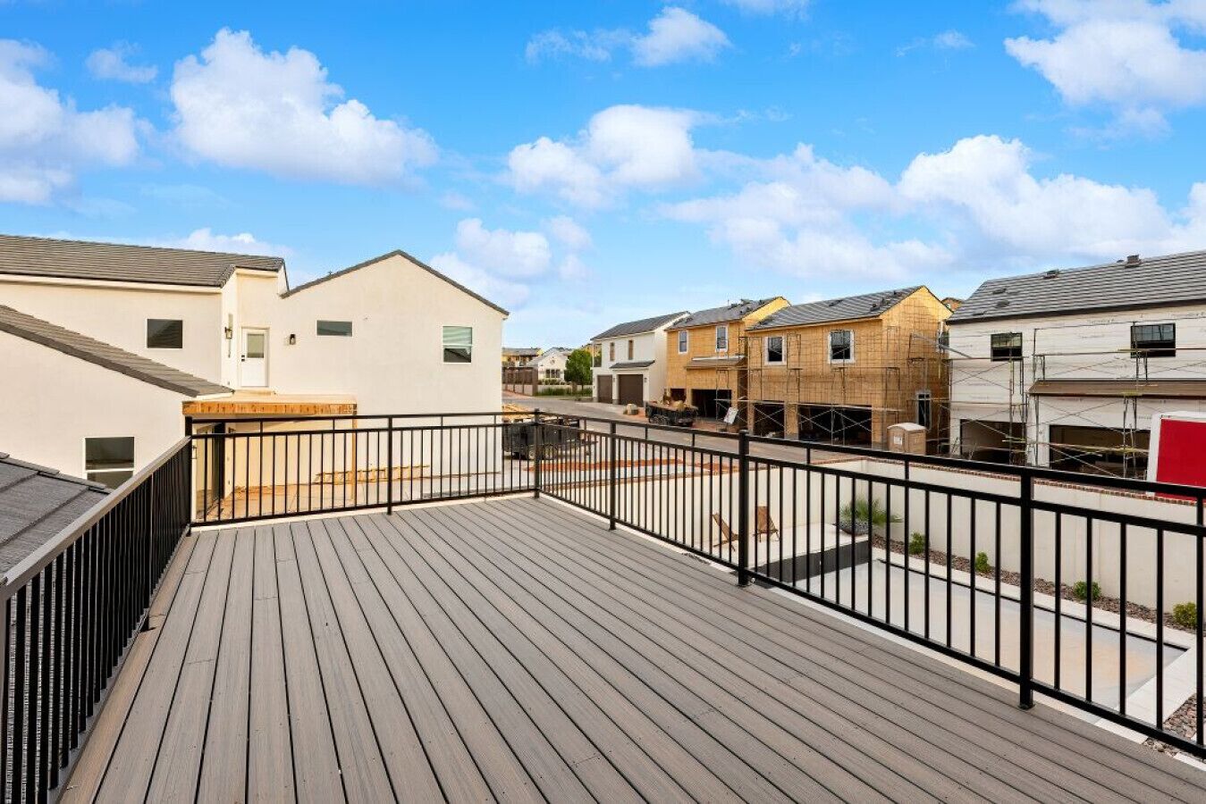 A residential area with a wooden deck, a fenced balcony, and houses in various stages of construction.