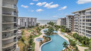 A resort with a large pool, multiple balconies, and a view of the ocean.