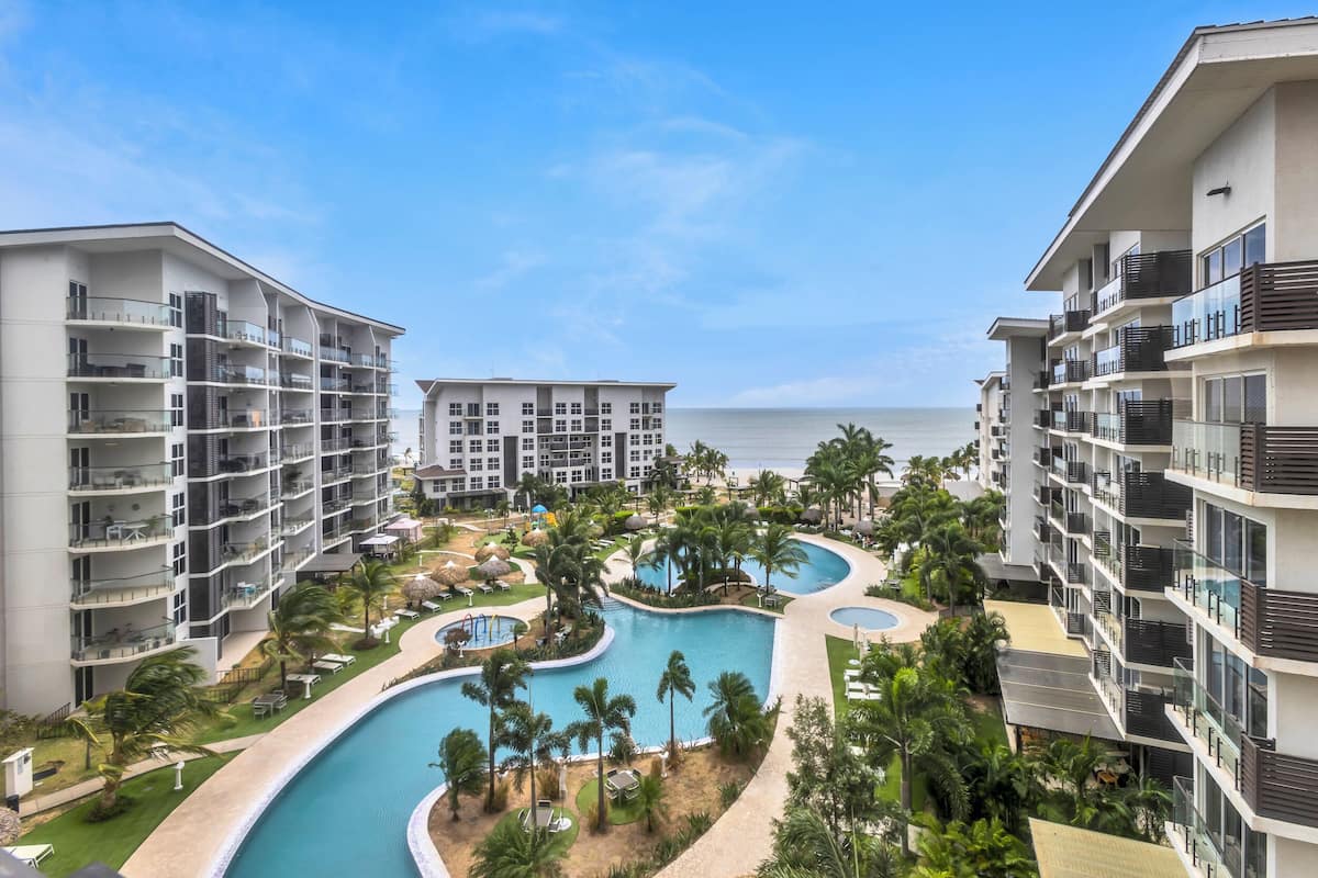 Un complexe hôtelier doté de plusieurs piscines, de palmiers et offrant une vue sur la plage.
