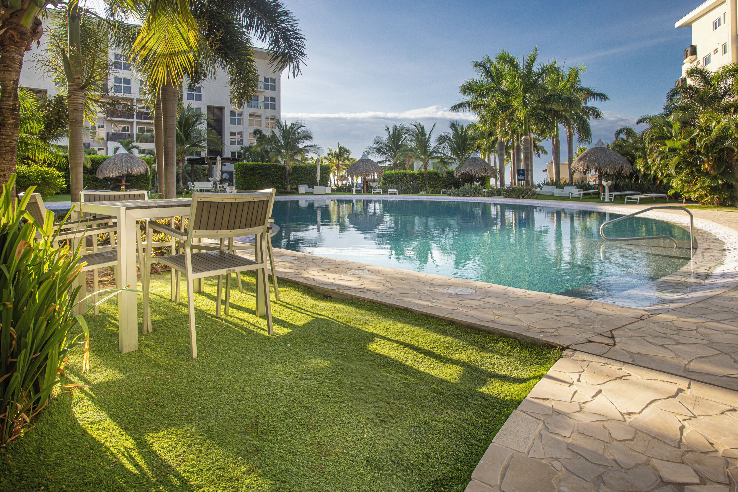 A pool area with lounge chairs, a table, and a well-maintained lawn.