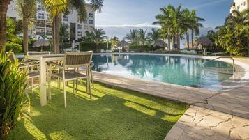 A pool area with lounge chairs, a table, and a well-maintained lawn.