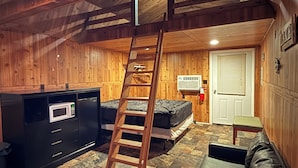 Een knus vakantiehuisje met een open slaapzolder, een ladder naar de slaapplek, een kitchenette en een open haard.