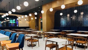 A modern restaurant interior with multiple tables and chairs, wooden accents, and hanging spherical lights. - Golden Mesa Hotel (Guymon)