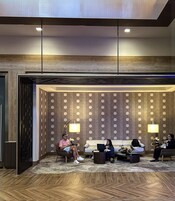 Un vestíbulo moderno con suelo de madera, una zona de estar con sofás y sillones, y una pared decorada con diseños circulares.