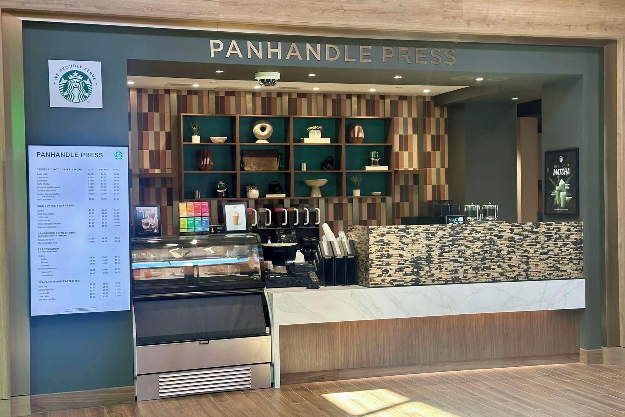 A PanHANDLE PRESS Starbucks with a menu board, espresso machines, and a variety of decorative items on shelves.