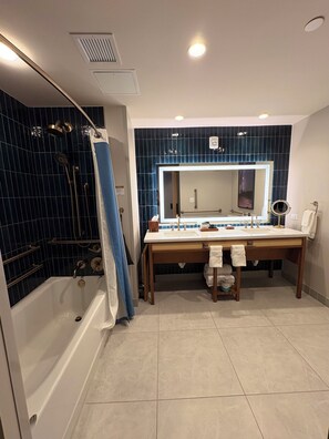 Un baño moderno con bañera, tocador con un espejo grande y zona de ducha.