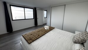 Et moderne hotelværelse med en stor seng, udsigt gennem vinduet og et lille natbord med et håndklæde.