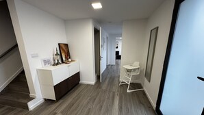 En gang med et hvidt receptionsskrivebord, en hvid stol og en trappe.