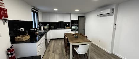 A compact kitchen with white cabinets, a wooden dining table, and a black countertop.