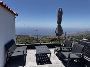 A balcony with a view of the sea, a table, and two chairs. - Hiking & Ocean (Calheta)
