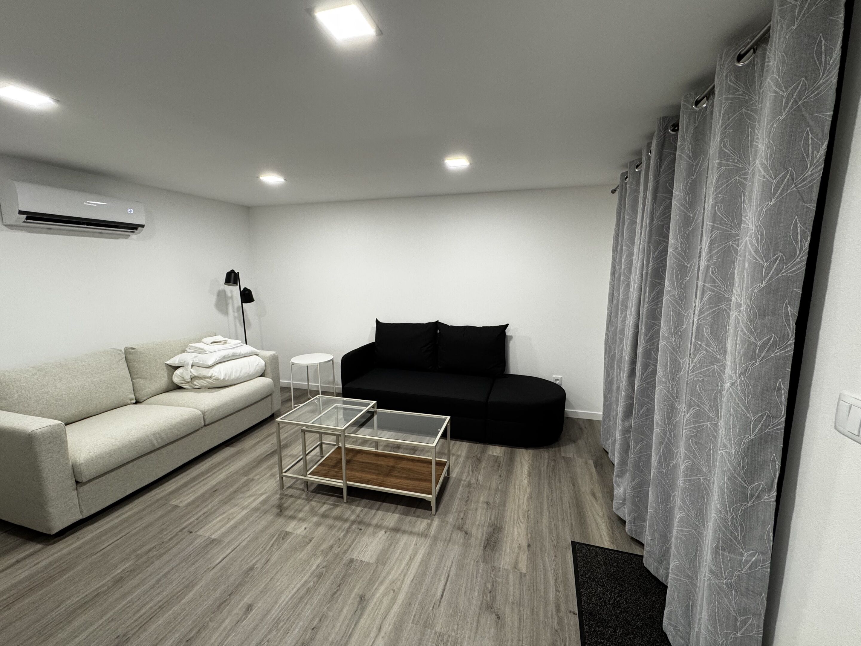 A modern living room with a sofa, a coffee table, and a black couch.