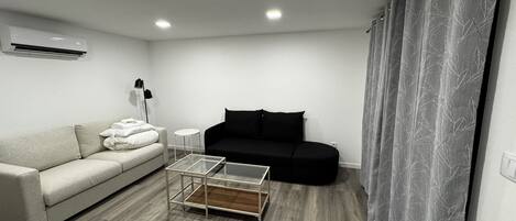 A modern living room with a sofa, a coffee table, and a black couch.