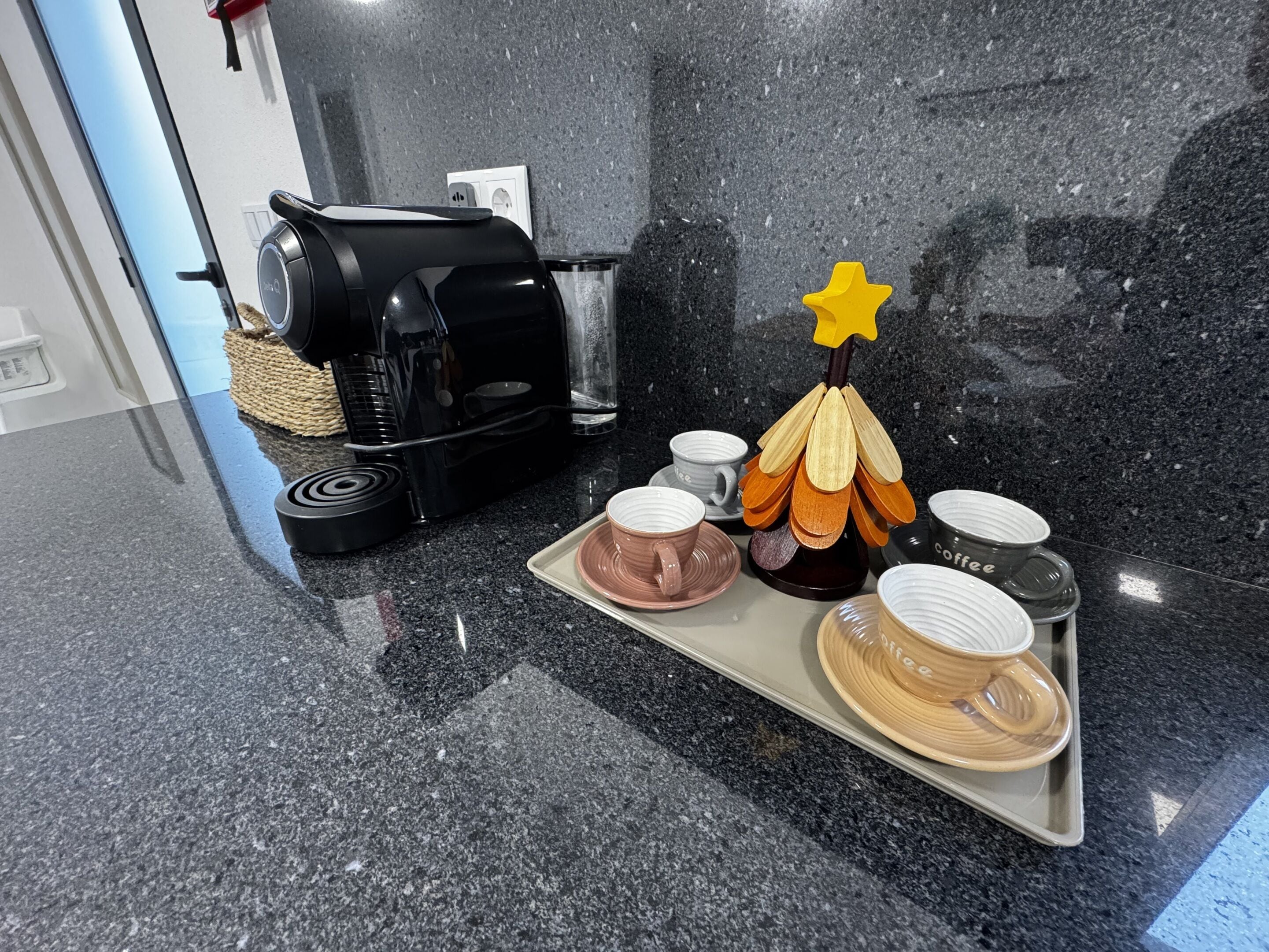 A kitchen counter with a coffee maker, a tray with cups, and a decorative item.