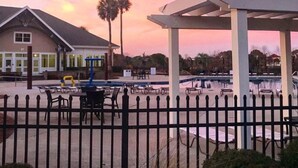 A pool area with a covered seating area, a building with a sloped roof, and palm trees. - 139 High Hammock (Seabrook Island)