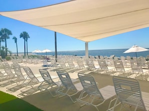 A beachside lounge area with rows of white lounge chairs and umbrellas, overlooking the ocean. - 139 High Hammock (Seabrook Island)