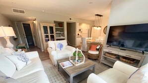 A living room with a sofa, armchairs, a coffee table, a television, and a kitchen area. - 139 High Hammock (Seabrook Island)