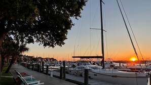 A marina with boats docked, a wooden walkway, and a sunset in the background. - 1022 Crooked Oaks (Seabrook Island)