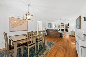 A dining area with a wooden table and chairs, a map on the wall, and a hanging light fixture. - 1155 Summer Wind Ln (Seabrook Island)