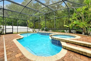 An indoor swimming pool with a glass ceiling, surrounded by brick flooring and lush greenery. - 11326 Cypress Trail Drive,orlando,3bed (Orlando)