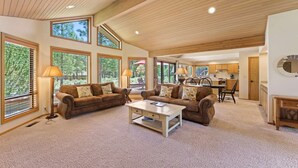 A spacious living room with large windows, a wooden ceiling, and a cozy seating area. - 10 Tan Oak (Bend)