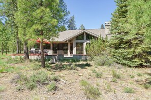 A cabin with a covered patio, surrounded by trees and a clear sky. - 10 Tan Oak (Bend)
