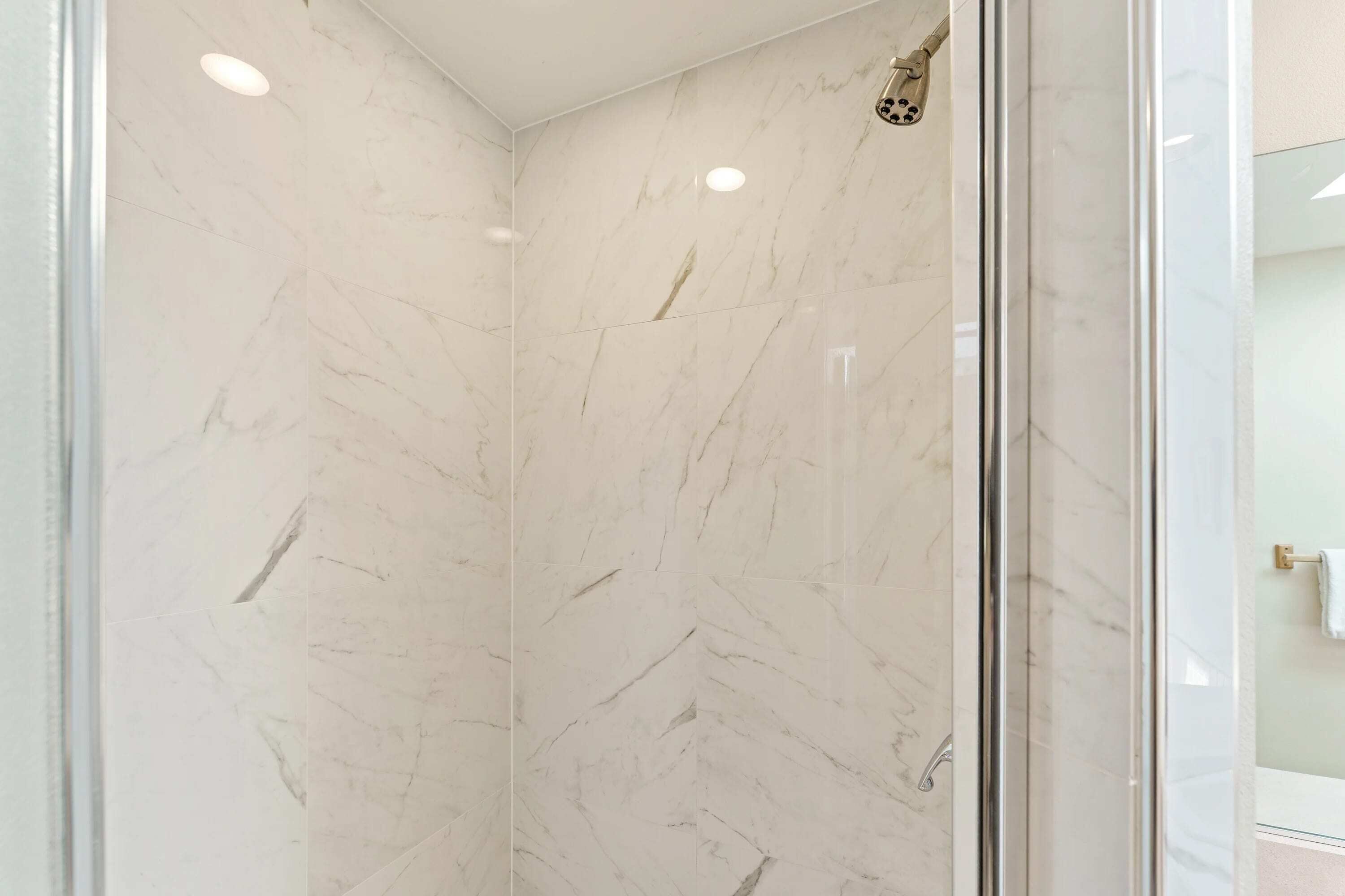 A glass-enclosed shower with marble walls and ceiling.